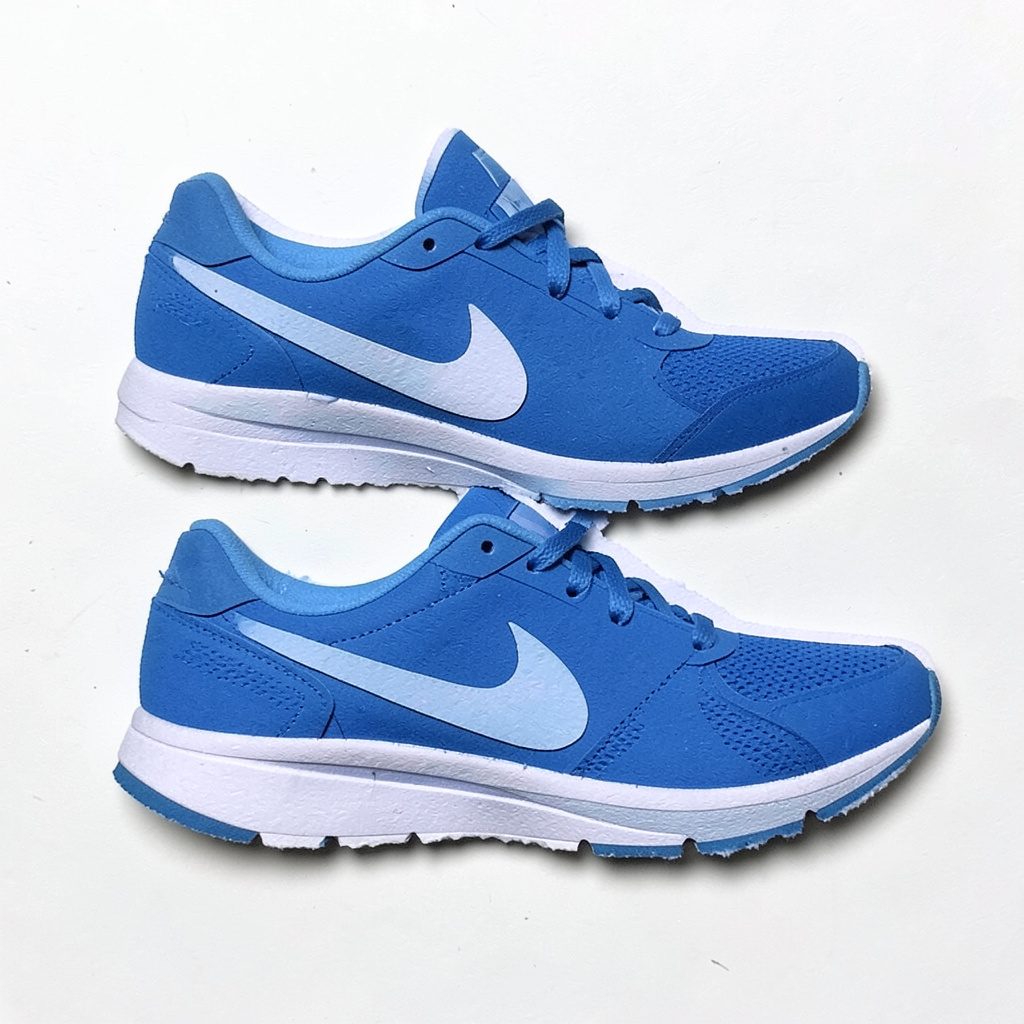 Layered paper cutout of blue running shoes on warm neutral background