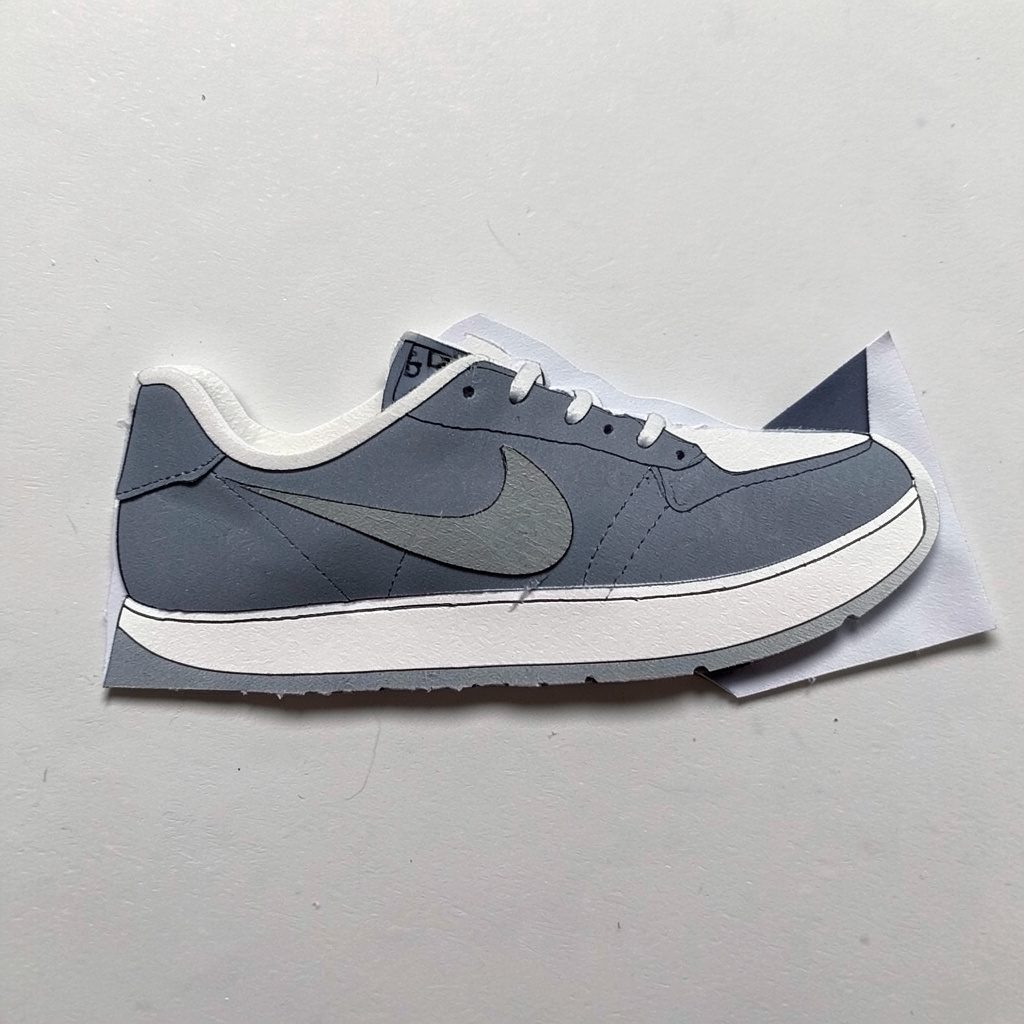 Layered paper cutout of dark blue performance running shoes on light background