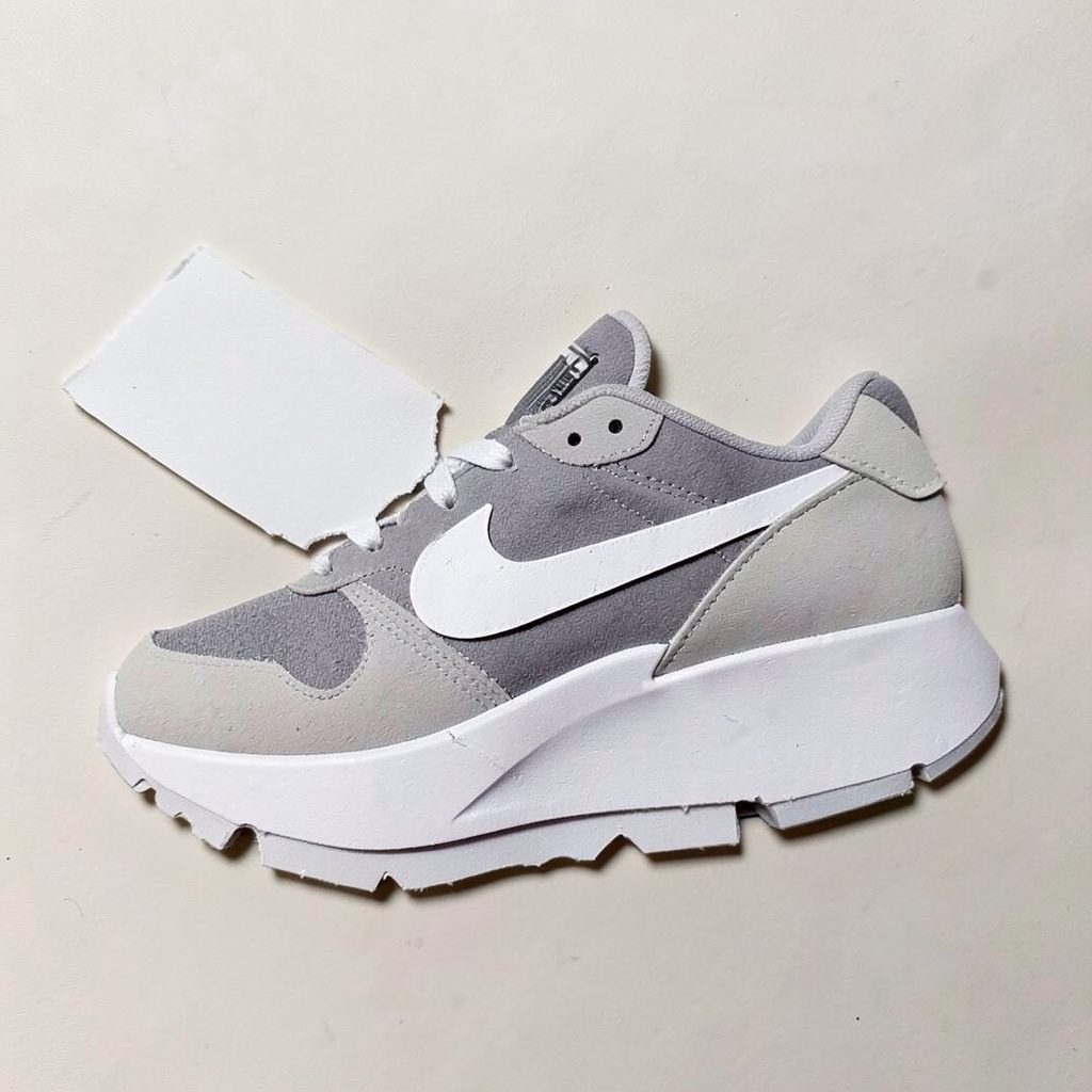 Layered paper cutout of blue performance running shoes on neutral background