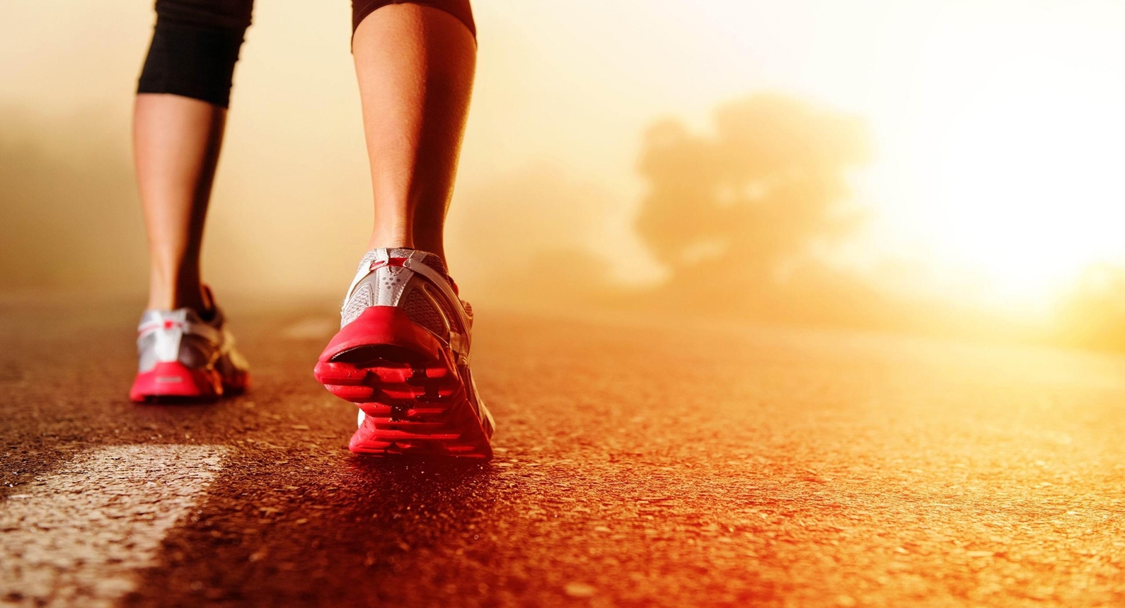 Layered paper cutout collage of running shoes and a sunrise road in warm orange and red tones